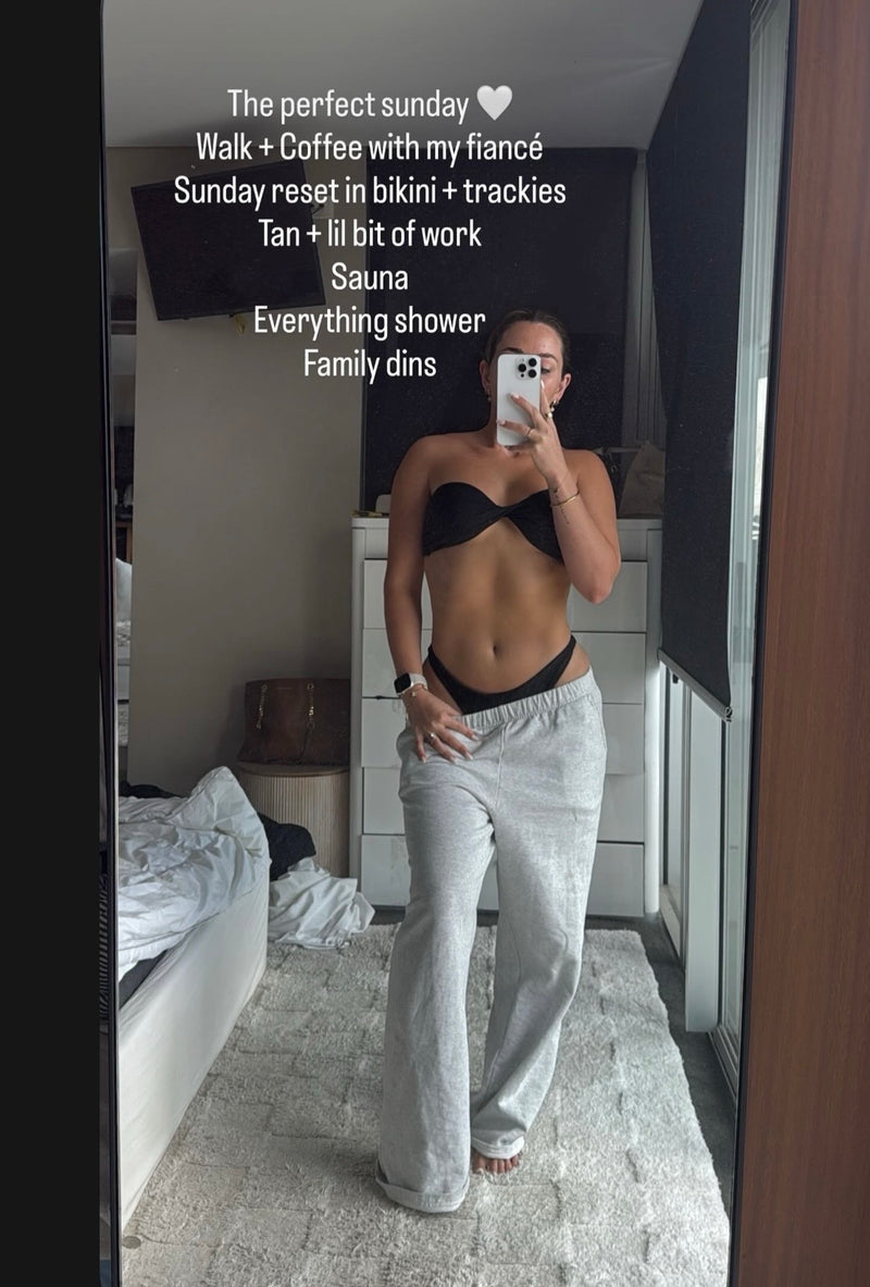 Mirror selfie of a girl in a bikini top and tracksuit bottoms looking tanned